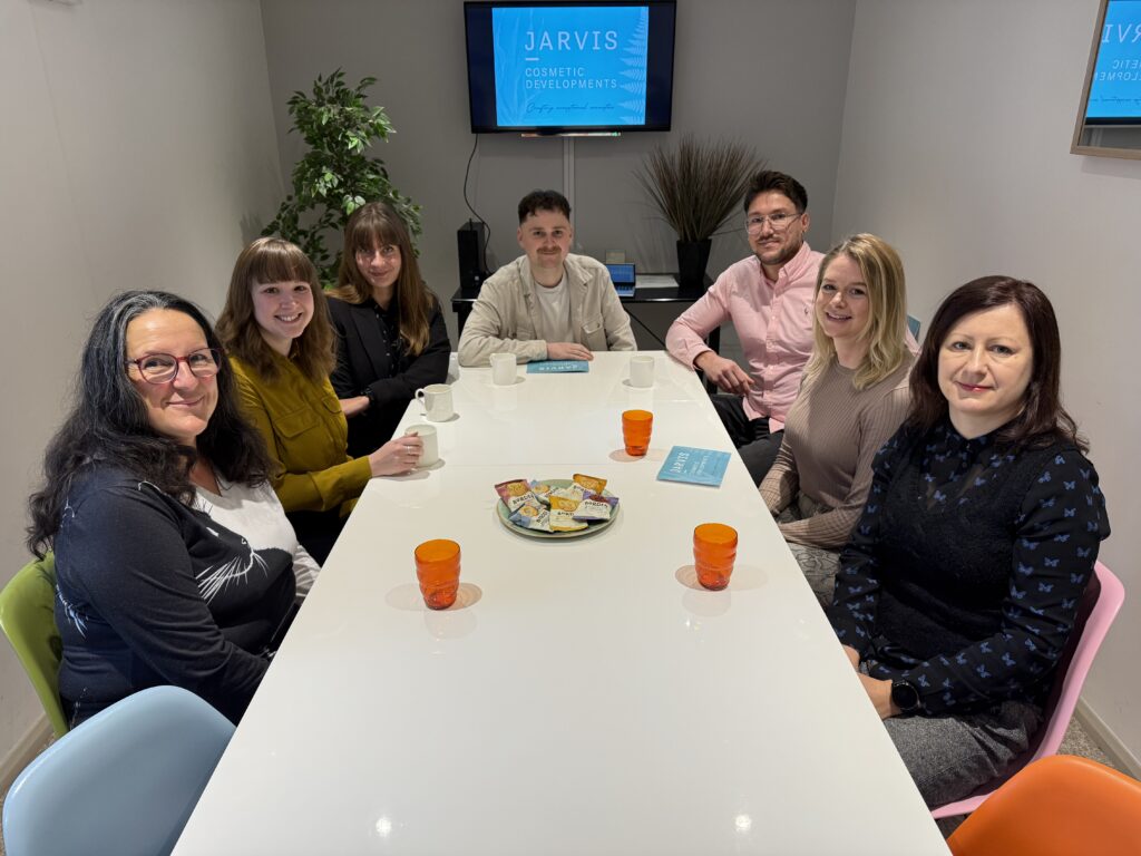 Jarvis Cosmetic Developments team collaborating around a meeting table demonstrating quality control and teamwork in UK cosmetic manufacturing.